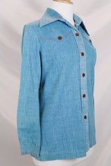 Women's vintage 1970's long sleeve medium wash denim chambray button up blouse with red contrast stitching and brass buttons.
