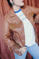 Women's vintage 1950's Custom Made by Milco-West, Portland, Oregon label long sleeve button up tan camel colored leather jacket with fringe trim. Western style with four pockets.