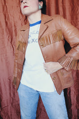 Women's vintage 1950's Custom Made by Milco-West, Portland, Oregon label long sleeve button up tan camel colored leather jacket with fringe trim. Western style with four pockets.