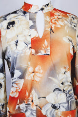 Women's vintage 1970's Pykettes label long sleeve floral printed tunic blouse with keyhole cut out front closure in grey, orange, and cream colors.