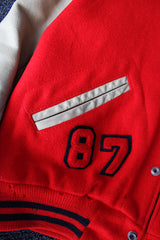 Men's vintage 1987 Nelson's Jackets, Portland, Oregon label long sleeve cream and red colored varsity letterman jacket in wool and nylon material. Has patches and pins.