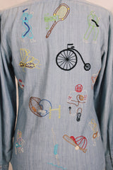 Men's or women's vintage 1970's BJ-R, Long Tail - Form Fit, Made in Hong Kong label long sleeve light blue denim chambray button up shirt with colored embroidery all over.