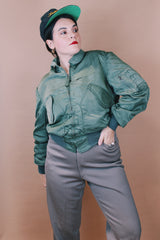 Men's vintage 1980's Flyer's CWU Military Flyer's Jacket, Made in USA label size medium long sleeve cropped length army green zip up bomber jacket with orange liner.