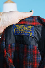 Men's vintage 1960's Pendleton short sleeve button up plaid shirt in a lightweight wool material. Red and grey colors with one chest pocket.