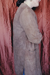 Women's vintage 1960's long length long sleeve tan brown colored suede jacket. No collar and suede buttons up the front.