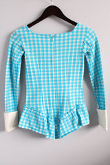 Women's vintage 1970's long sleeve light blue and white checkered bodysuit with ruffled trim, cuffs, and decorative buttons.