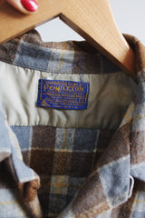 Men's vintage 1960's Pendleton size XL long sleeve button up wool shirt in all over blue and brown plaid print. Two chest pockets.