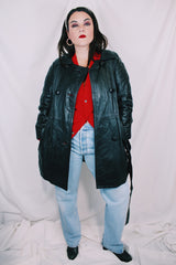 Women's vintage 1970's long sleeve double breasted long length black leather jacket with fabric buttons and side pockets. Matching belt.