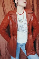 Women's vintage 1970's long sleeve button up burnt orange suede and leather jacket. Long length with matching belt.