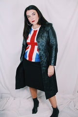 Women's vintage 1970's knee length long sleeve black leather trench coat with double lapel and button front closure.