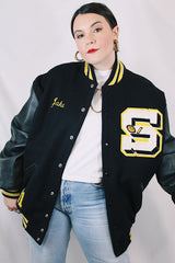Men's or women's vintage 2000's Settlemein's, Portland, Oregon label long sleeve black varsity letterman jacket with yellow trim.