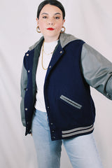 Men's or women's vintage 1980's Settlemein's, Portland, Oregon label long sleeve navy and grey varsity letterman jacket in wool, leather, and nylon. Snap buttons and hood.