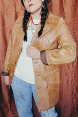 Women's or men's vintage 1970's Lou Pollack, Made in Spain label long sleeve long length tan camel brown colored leather blazer jacket with tortoise buttons up the front.
