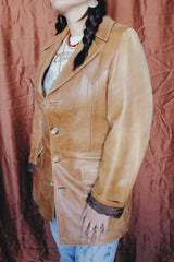 Women's or men's vintage 1970's Lou Pollack, Made in Spain label long sleeve long length tan camel brown colored leather blazer jacket with tortoise buttons up the front.