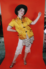 Women's vintage 1960's short sleeve gold yellow stain button up blouse with black trim and black fabric buttons.