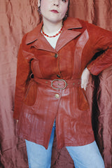 Women's vintage 1970's long sleeve button up burnt orange suede and leather jacket. Long length with matching belt.