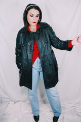 Women's vintage 1970's long sleeve double breasted long length black leather jacket with fabric buttons and side pockets. Matching belt.
