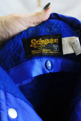 Women's or men's vintage 1980's Swingster, World of Wearables label long sleeve lightweight bright blue nylon windbreaker jacket with logo on left chest, popper buttons, and furry fleece liner.
