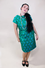Women's vintage 1960's short sleeve midi length green and blue stain dress. Subtle floral print and scalloped waist. Zipper in the back.