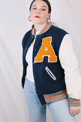 Men's vintage 1960's Skookum Letterman, Centralia Knitting Mills, Centralia Washington label long sleeve navy, white, and orange varsity letterman jacket in wool and leather material.