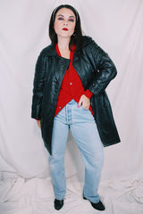 Women's vintage 1970's long sleeve double breasted long length black leather jacket with fabric buttons and side pockets. Matching belt.