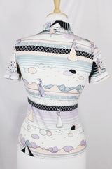 Women's vinttage 1970's Fritz label short sleeve button up blouse with dagger collar and all white, blue, and purple novelty print in a lightweight polyester material.