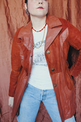 Women's vintage 1970's long sleeve button up burnt orange suede and leather jacket. Long length with matching belt.