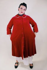 Women's vintage 1960's long length long sleeved red velvet robe duster with a peter pan collar and pink stain trim. Buttons up the front.