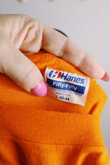 Women's or men's vintage 1980's Hanes, Fifty-Fifty, Made in USA label short sleeve orange tee with graphic on the front in black and white in a Polyester and cotton material.