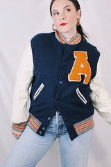 Men's vintage 1960's Skookum Letterman, Centralia Knitting Mills, Centralia Washington label long sleeve navy, white, and orange varsity letterman jacket in wool and leather material.