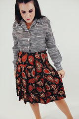 Knee length pleated skirt in forest green, red, and white paisley print front