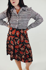 Knee length pleated skirt in forest green, red, and white paisley print front
