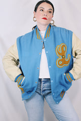 Men's or women's vintage 1994 Settlemien's, Portland, Oregon label long sleeve baby blue and cream varsity letterman jacket with yellow trim in leather and wool material.