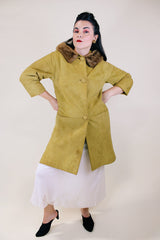 Women's vintage 1960's long sleeve long length button up suede coat with fur trim on collar. Mustard yellow color. Has pockets and side slits.