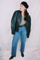 Men's or women's vintage 1980's long sleeve black leather moto jacket with all over silver hardware. Snap buttons, pockets with zippers, and zipper closure.