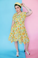 Women's vintage 1960's short sleeve polyester material mini length dress with all over green, orange, and yellow floral print.