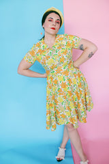 Women's vintage 1960's short sleeve polyester material mini length dress with all over green, orange, and yellow floral print.