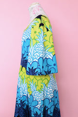 Women's vintage 1970's Sears Hawaiian Fashions label short sleeve maxi length cotton material Hawaiian print dress in green, blue, and white print with a square neckline.