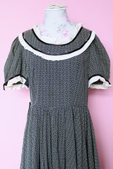 Women's vintage 1940's short sleeve maxi length cotton material prairie style dress with white and black ribbon trim around neckline and cuffs. Scalloped hem.