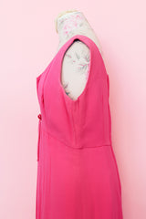 Women's vintage 1960's sleeveless mini length babydoll dress in bright pink with V shaped neckline and bow on chest.