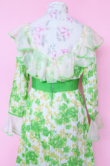 Women's vintage 1970's long sleeve maxi length floral print dress in green and white colors. Sheer white ruffle trim, ribbon belt.