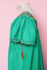 Women's vintage 1970's short sleeve cotton material green short sleeve ankle length dress with orange embroidery and a square neckline and puff sleeves.