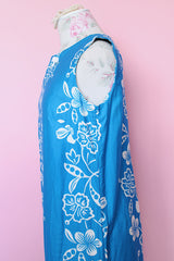 Women's vintage 1960's Made in Hawaii for Andrade Resort Shops Waikiki label sleeveless ankle length blue Hawaiian print dress with all over white floral print and white trim.