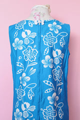 Women's vintage 1960's Made in Hawaii for Andrade Resort Shops Waikiki label sleeveless ankle length blue Hawaiian print dress with all over white floral print and white trim.