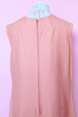 Women's vintage 1960's midi length sleeveless peach orange colored shirt dress with white beads across chest creating a floral print.