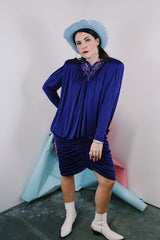Women's vintage 1980's long sleeve knee length drapey purple slinky polyester dress with beaded trim neckline.