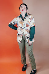 Men's vintage 1970's Jandy Place, Bardon Inc. label short sleeve button up shirt with a pointy collar in a silk like polyester material cream colored with all over brown and blue abstract print.