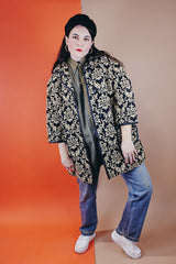 Women's vintage 1960's black and tan tapestry printed button up coat with black leather trim, two front pockets, and a rounded peter pan collar