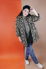 Women's vintage 1960's black and tan tapestry printed button up coat with black leather trim, two front pockets, and a rounded peter pan collar