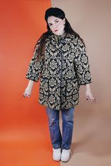 Women's vintage 1960's black and tan tapestry printed button up coat with black leather trim, two front pockets, and a rounded peter pan collar